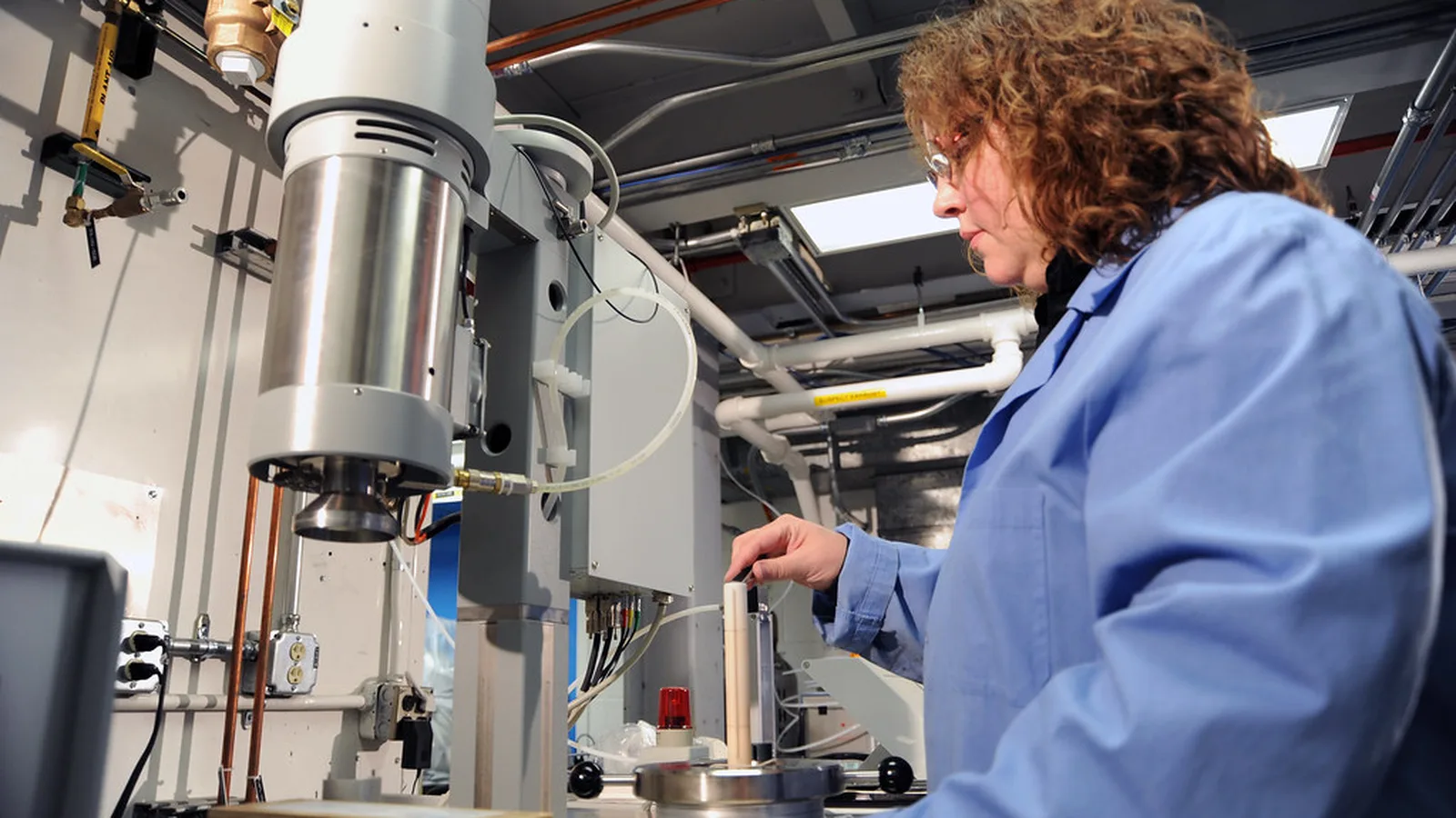 Researcher in a lab coat operating analytical instrumentation in a laboratory